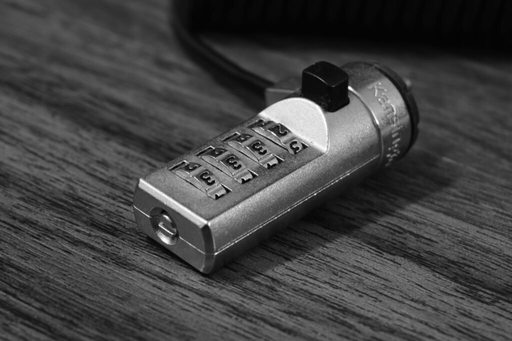 Black and white image of a metal combination lock on a wooden background.