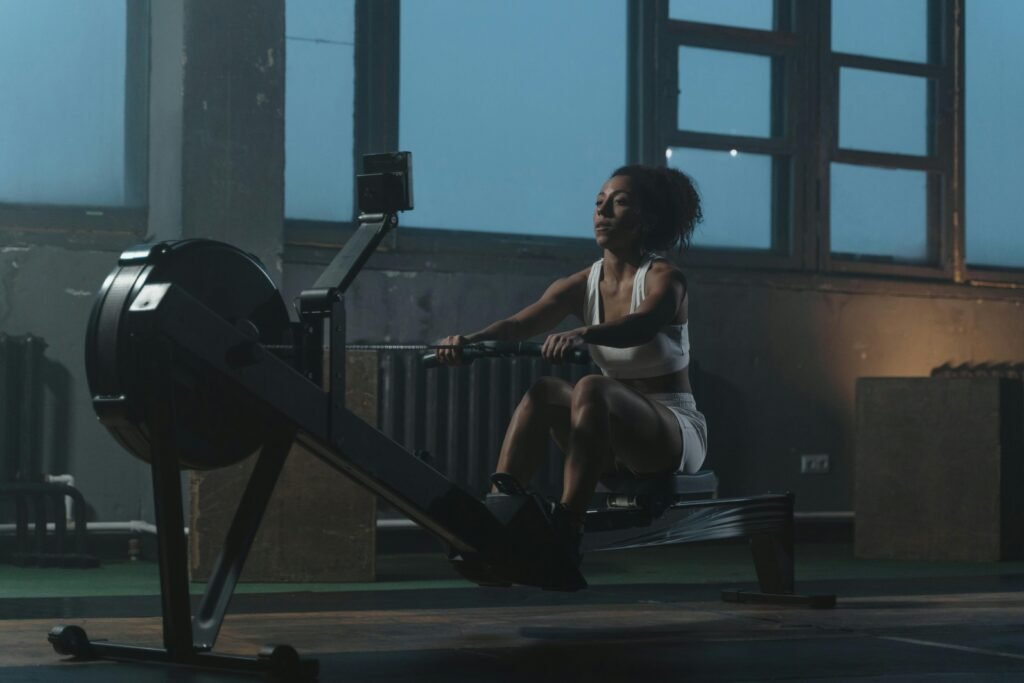 A woman working out on a rowing machine indoors, showcasing strength and focus.