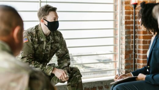 US Army personnel in a group therapy session with mental health professionals indoors.