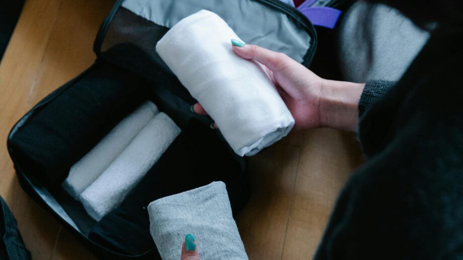 Person packing and organizing clothes in a suitcase for travel.